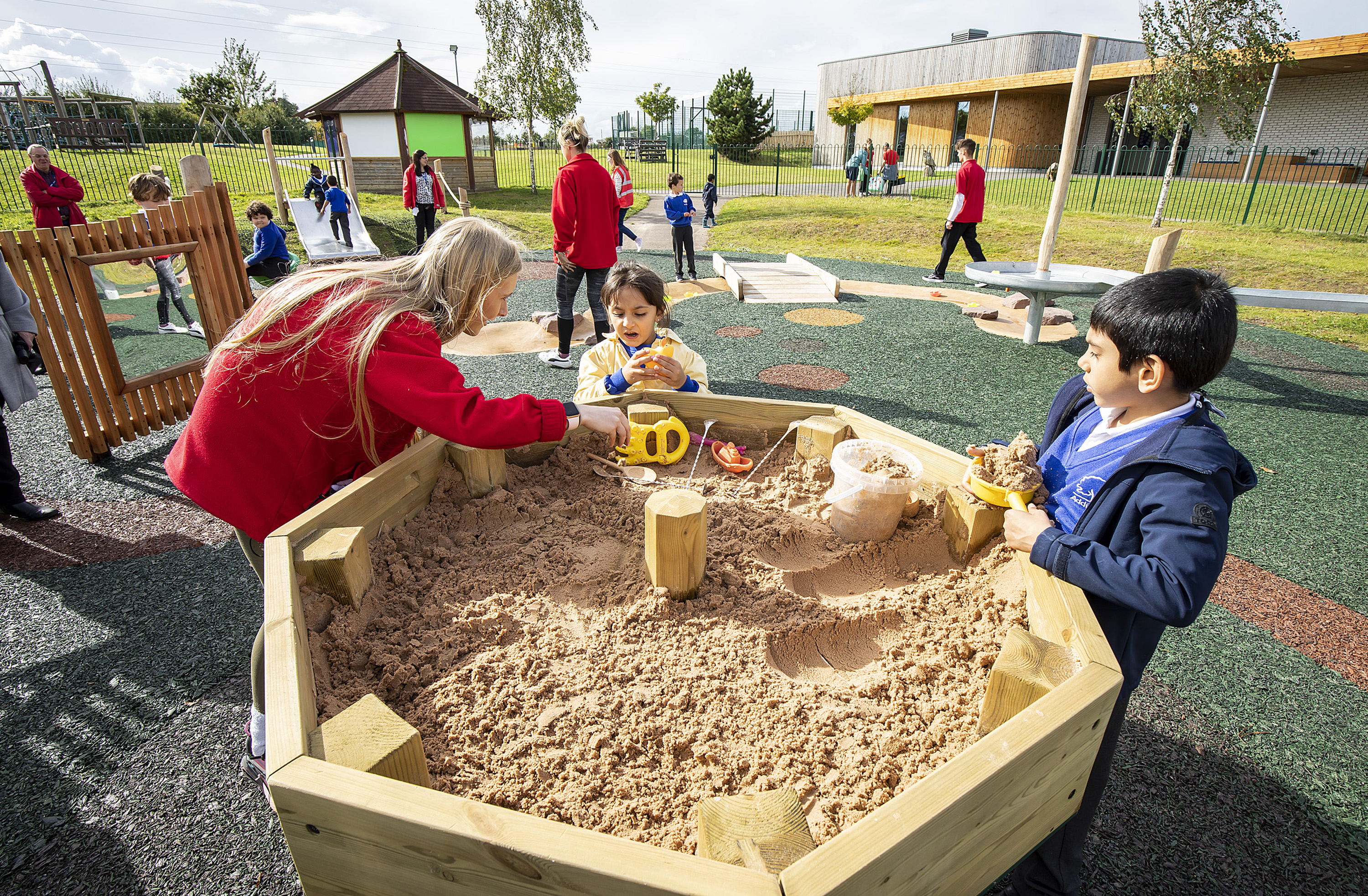Children and teacher playing with sand in the sensory garden at Addington School