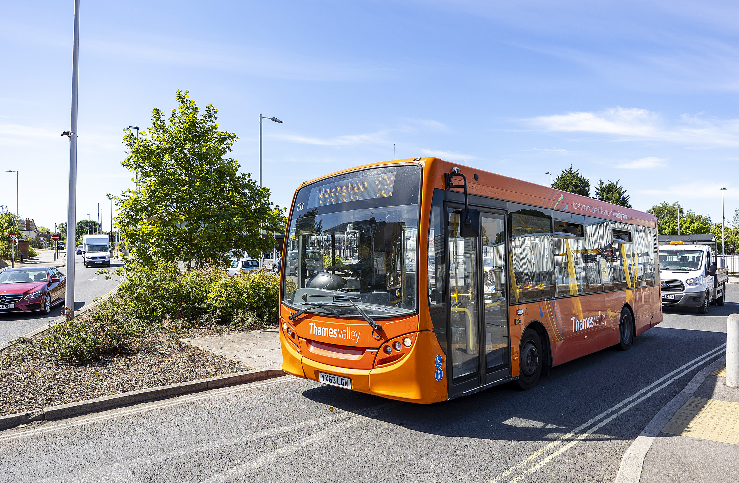 A bus pulling out of a stop on a sunny day