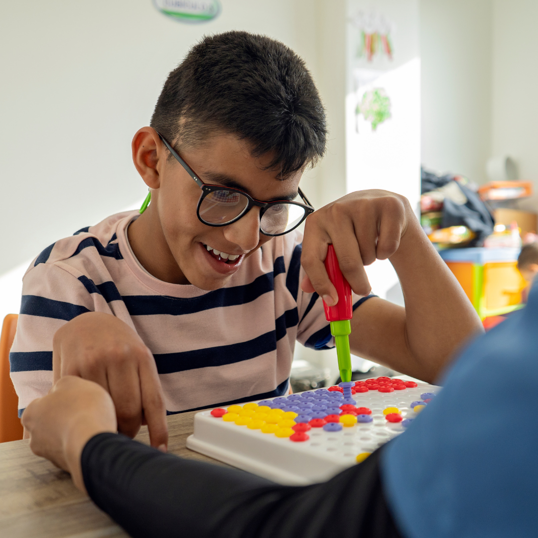 Boy sat at a table playing with a peg board