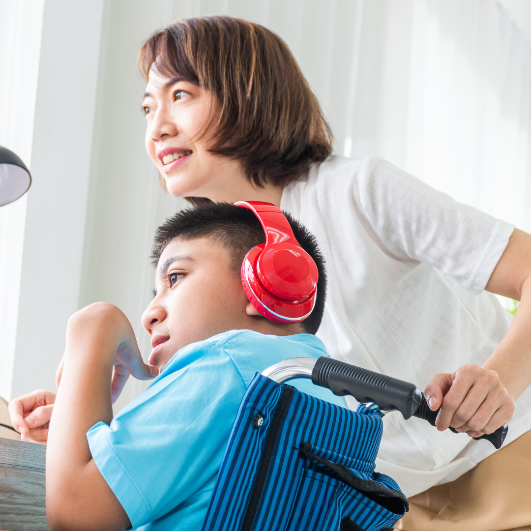 A boy wearing headphones with a woman standing next to him