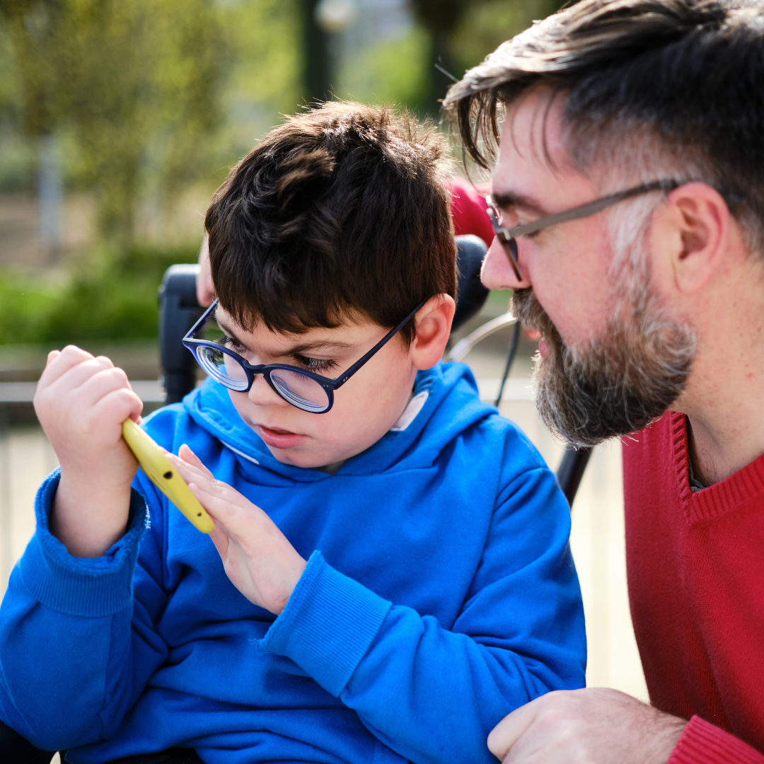 A man crouching next to a boy who is looking intently at a toy