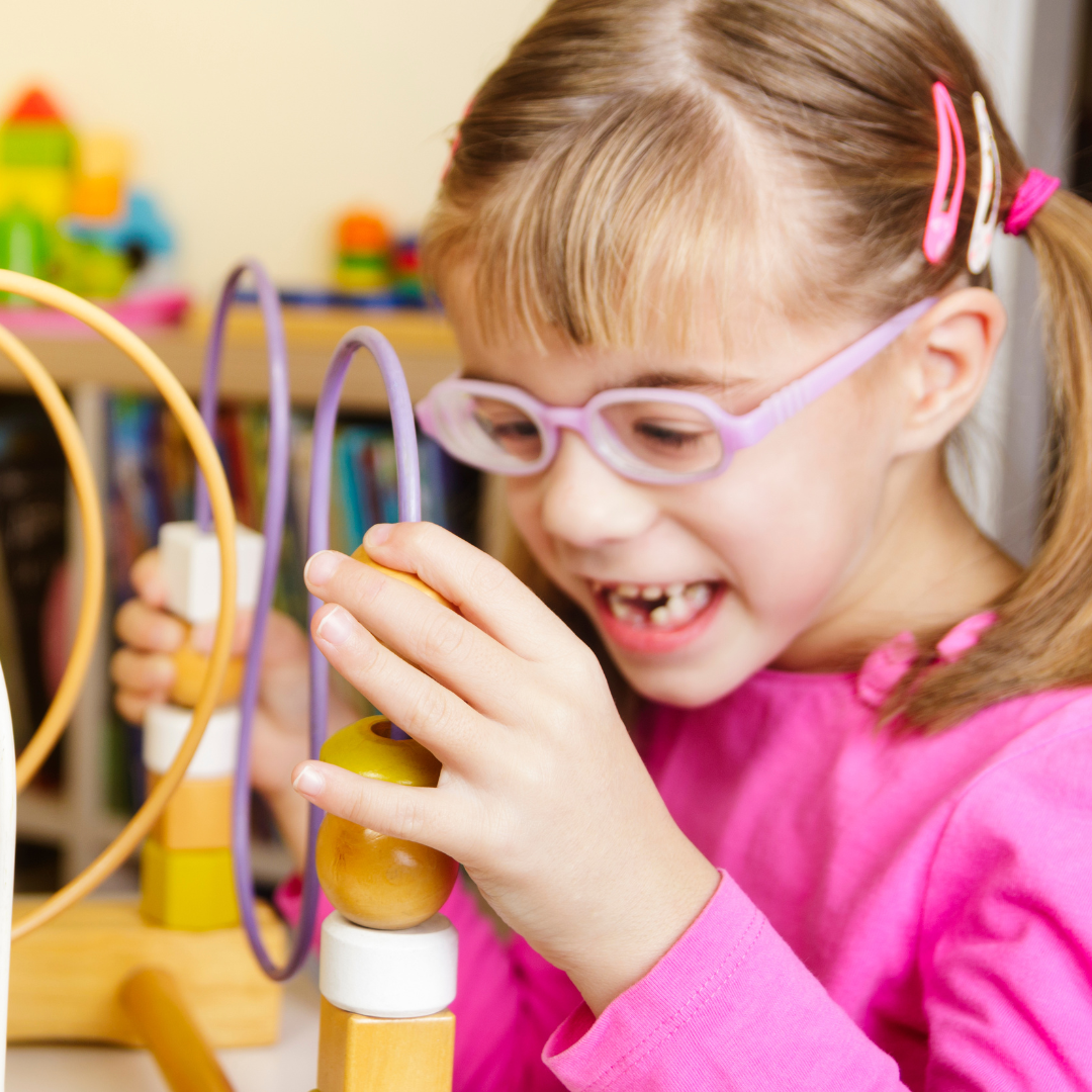 A girl smiles as she plays with a bead run