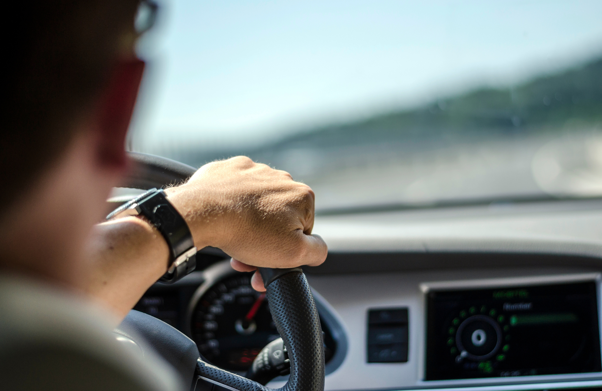 close-up shot of a driver's hand on the steering wheel