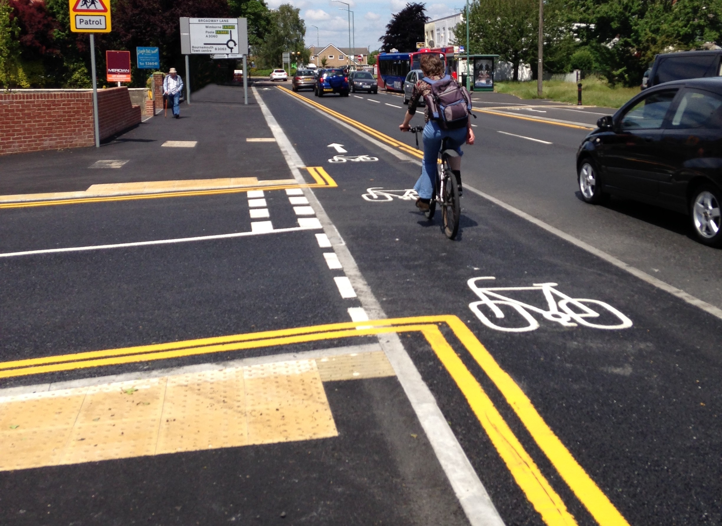 A raised cycle path passes a side junction with the cyclist given priority over emerging traffic