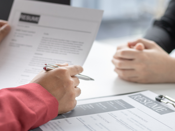 A person holding a resume opposite a candidate 