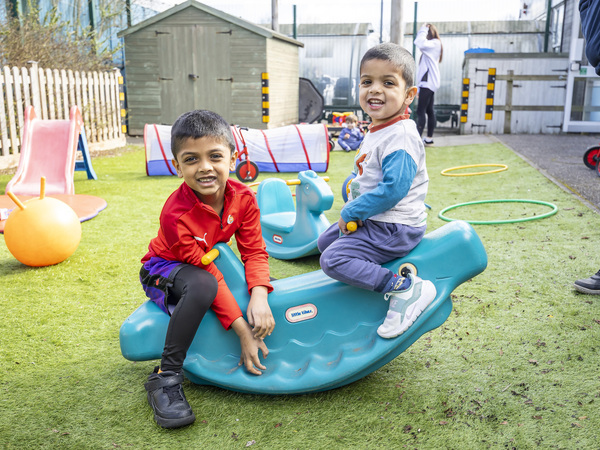 Two children at the family hub celebration event on a seesaw toy